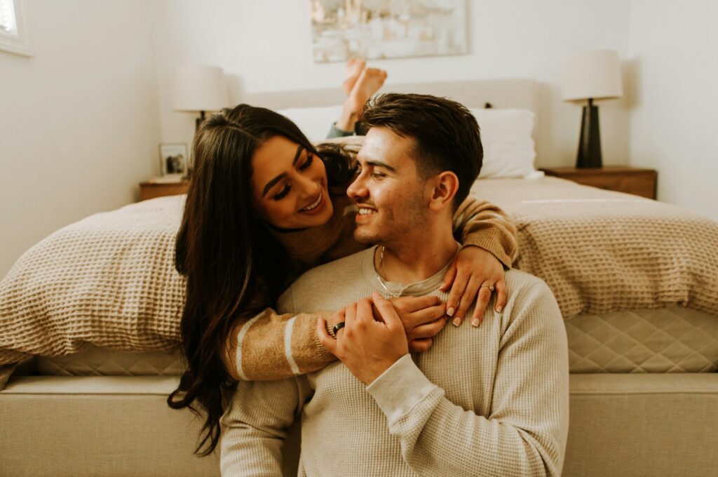 a man and a woman sitting on a bed together